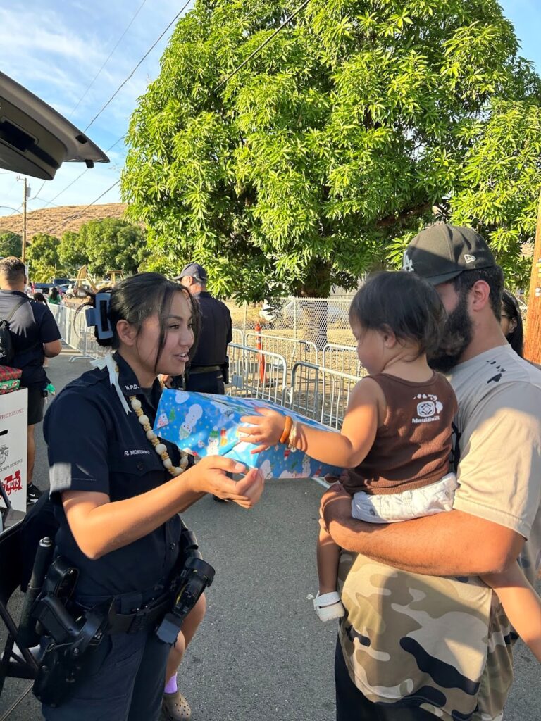 OFFICER GIVING A GIFT TO A CHILD AT THE OPERATION BLUE LIGHT CHRISTMAS EVENT